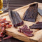 Fresh sliced Traditional Beef Biltong on wooden cutting board with beer, by Simply African Food for The Biltong Merchant