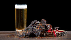 chilli biltong chips with chillies on a wooden board with beer
