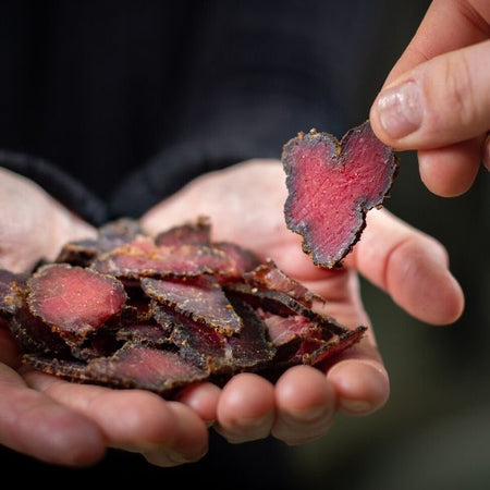 Succulent slices of traditional biltong being offered by clean hands with heart-shaped piece of fresh biltong being taken