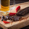 Fresh sliced Peri Peri Beef Biltong with beer & chillies on wood, by Simply African Food for The Biltong Merchant