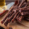 Traditional Fresh Droëwors biltong on wood table with cutting knife & beer, by Simply African Food for The Biltong Merchant